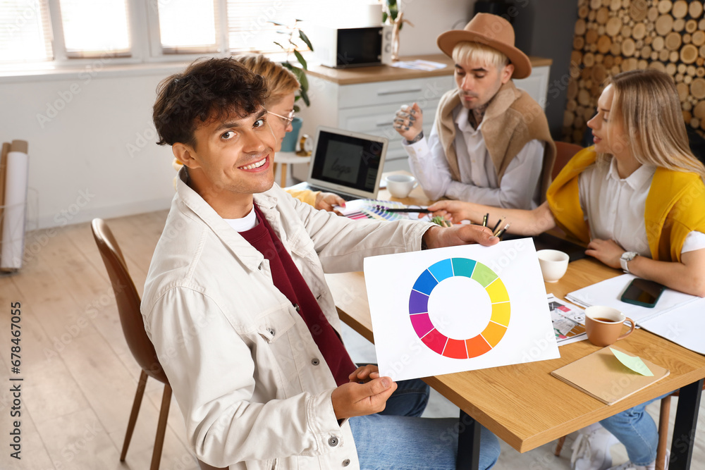 Male graphic designer working with co-workers at table in office