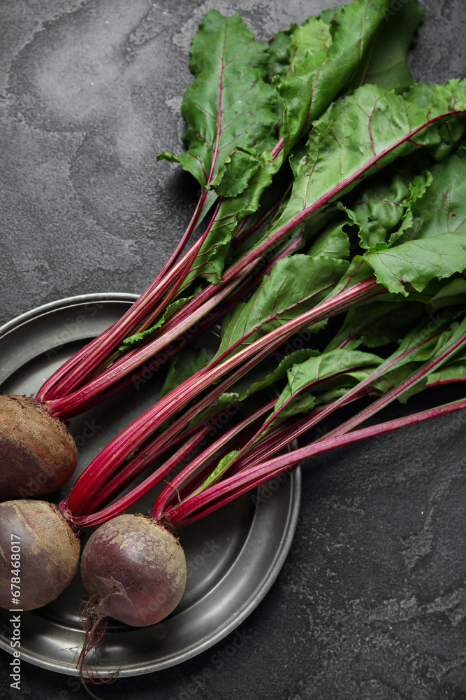 Plate with fresh beetroots on black table