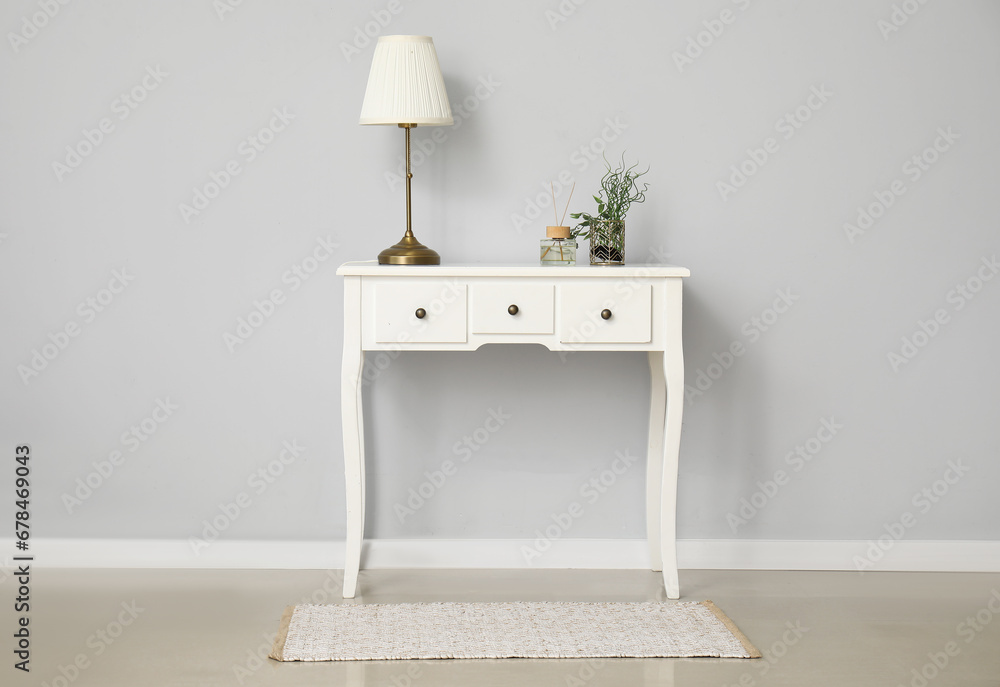 Dressing table with lamp near white wall