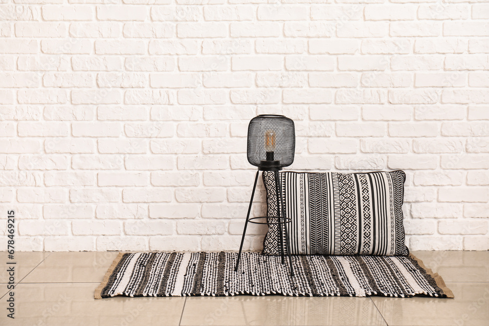 Small lamp on rug near white brick wall