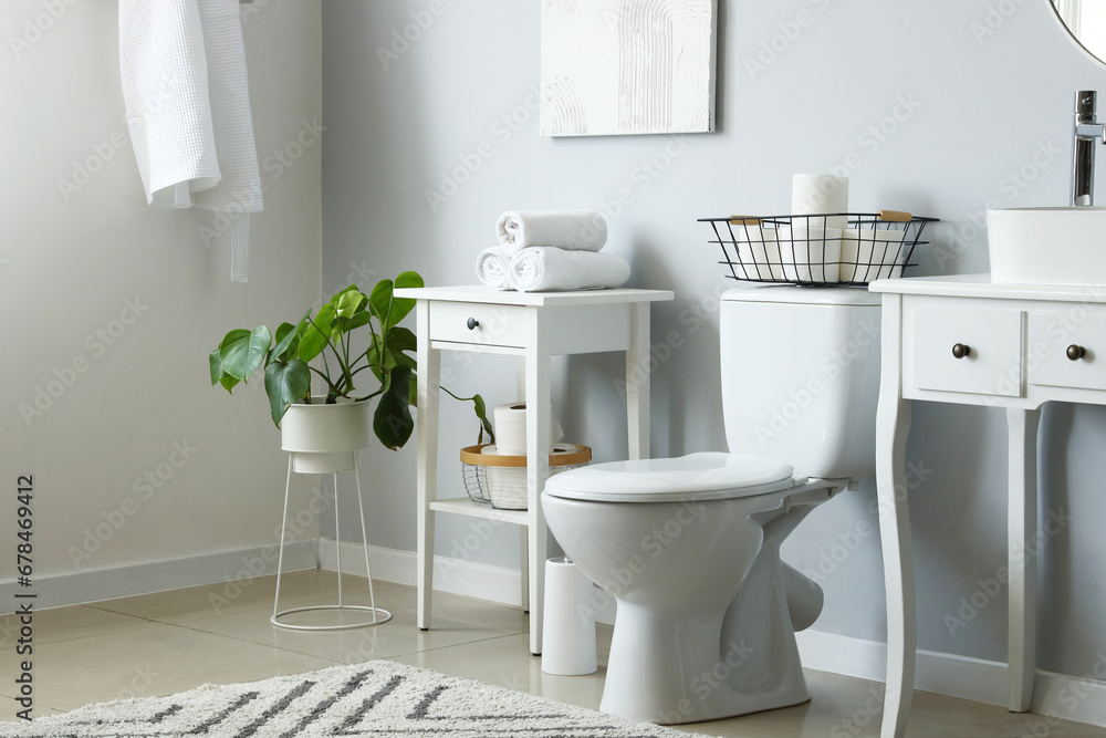 Interior of light restroom with ceramic toilet bowl and vanities