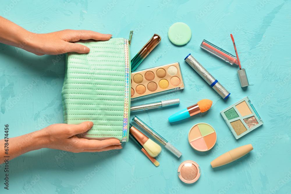 Woman holding bag with decorative cosmetics on blue background