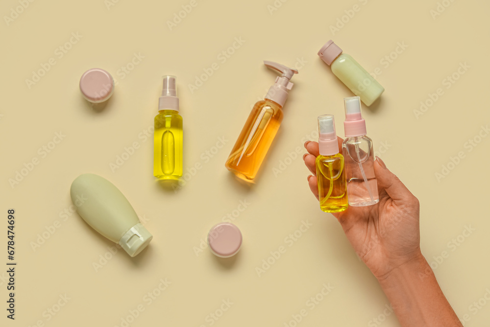 Female hand with with travel cosmetics kit on color background