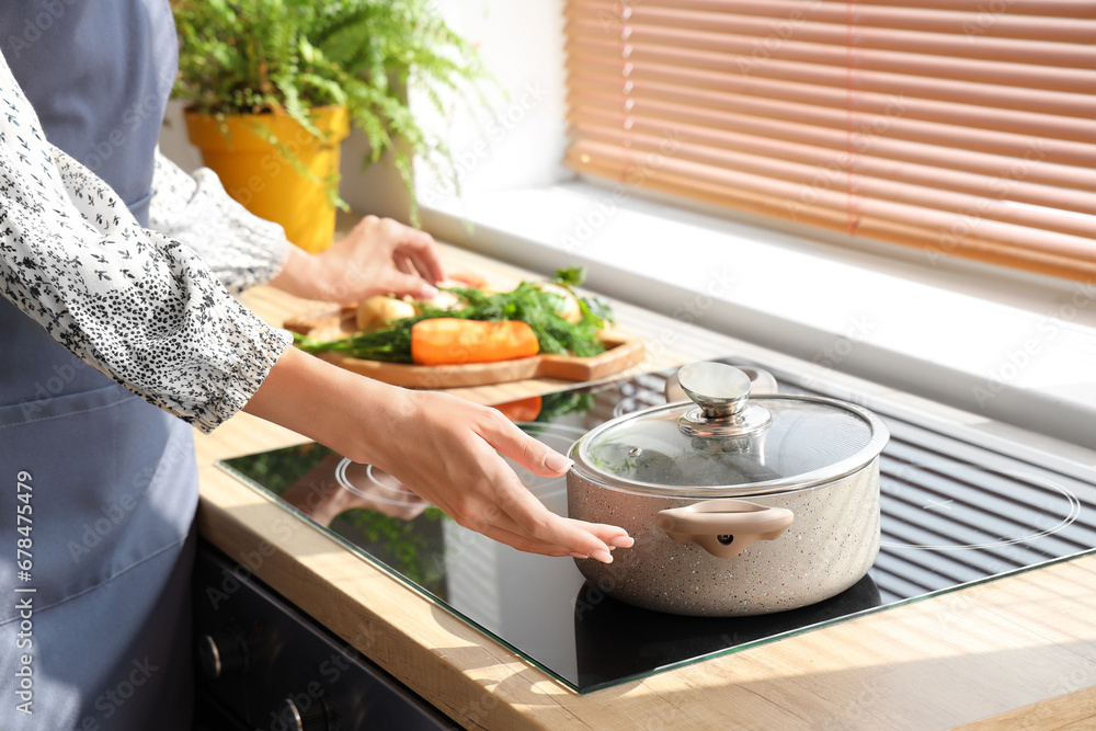 Young woman cooking chicken soup on stove in kitchen, closeup