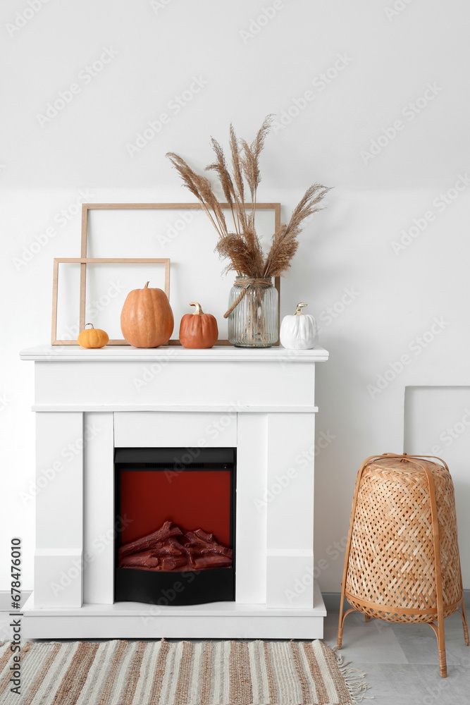 Vase with pampas grass, frames and pumpkins on mantelpiece in living room