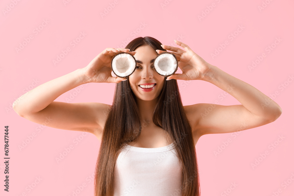 Beautiful young woman with coconut on pink background