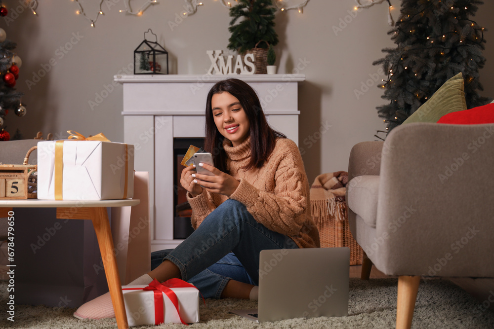 Young woman with credit cards shopping online for Christmas at home