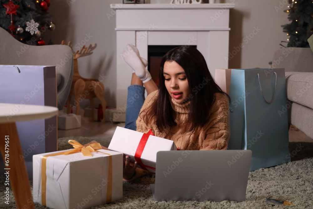 Young woman with Christmas presents and laptop at home. Online shopping