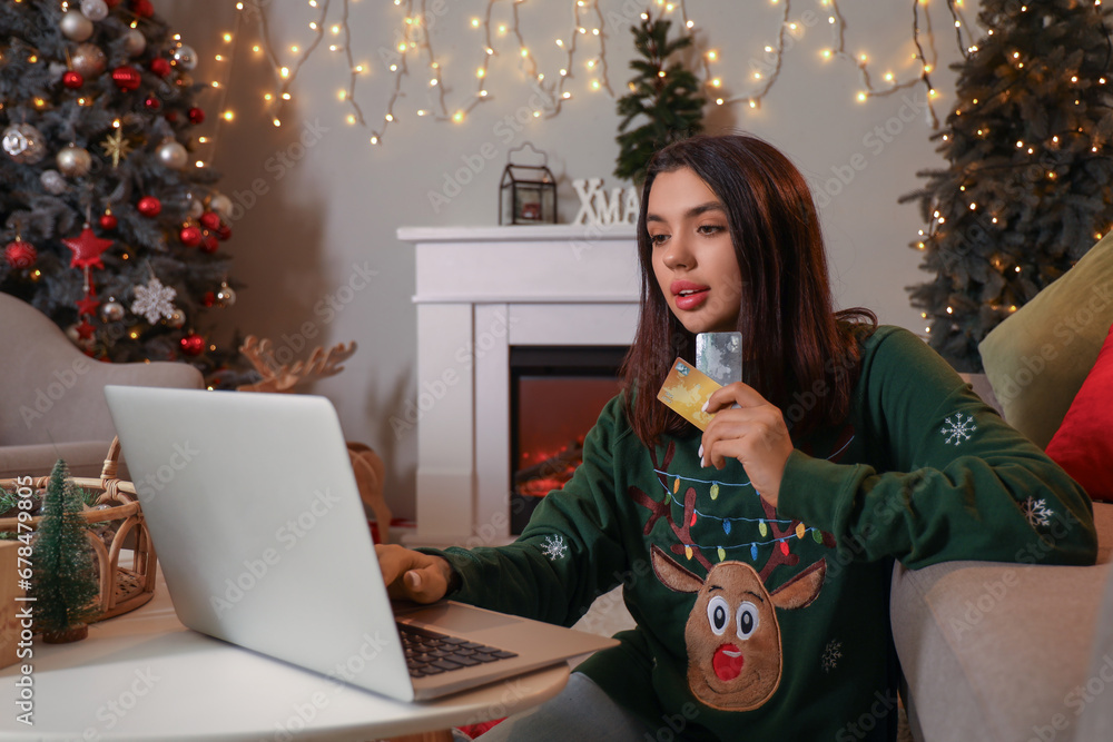 Young woman with credit cards and laptop shopping online for Christmas at home