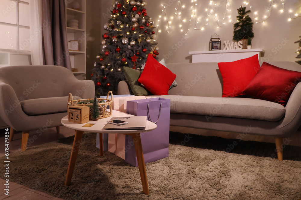 Interior of living room with Christmas trees, sofa and shopping bags