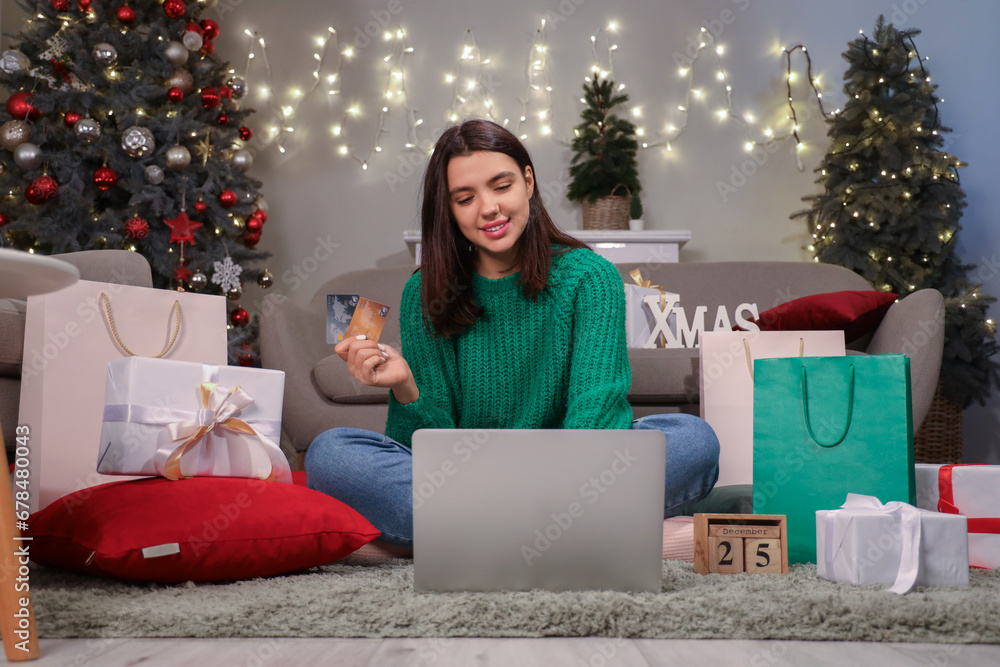 Young woman with credit cards and laptop shopping online for Christmas at home