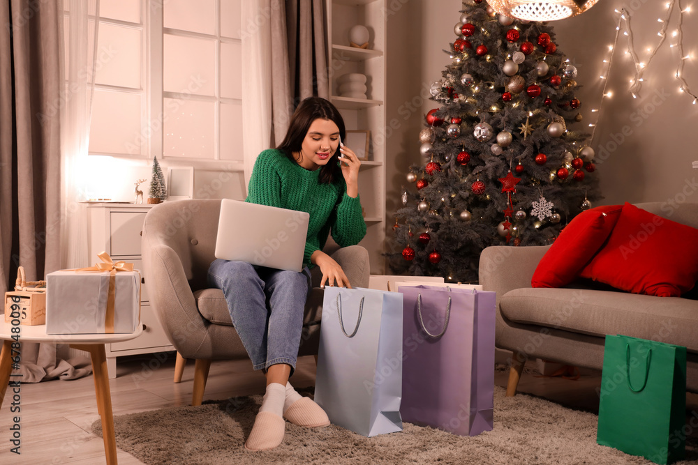 Young woman with mobile phone shopping online for Christmas at home