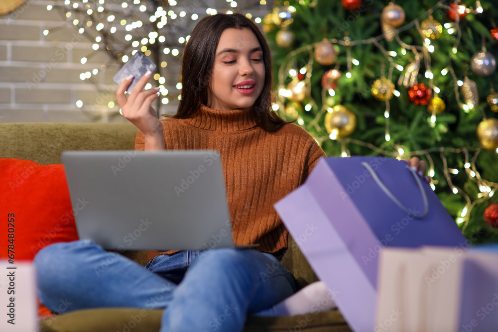 Young woman with credit card shopping online for Christmas at home