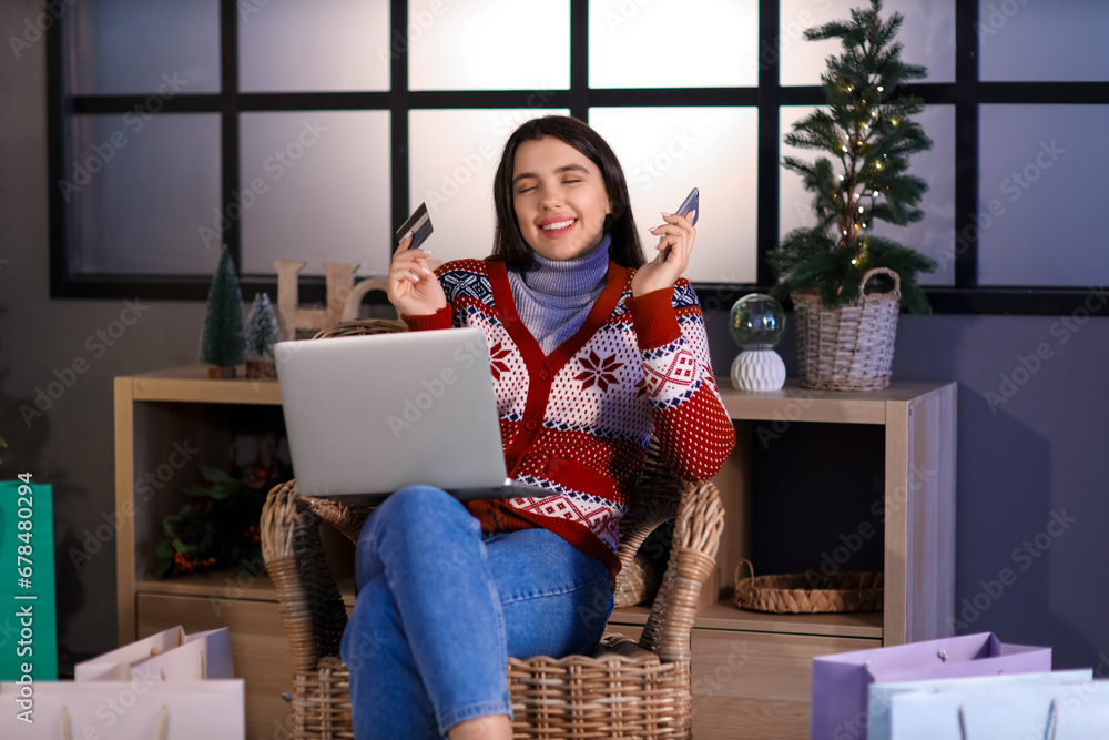 Young woman with credit card and mobile phone shopping online for Christmas at home