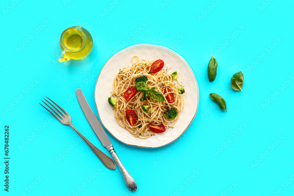 Plate of tasty pasta with broccoli and tomatoes on blue background