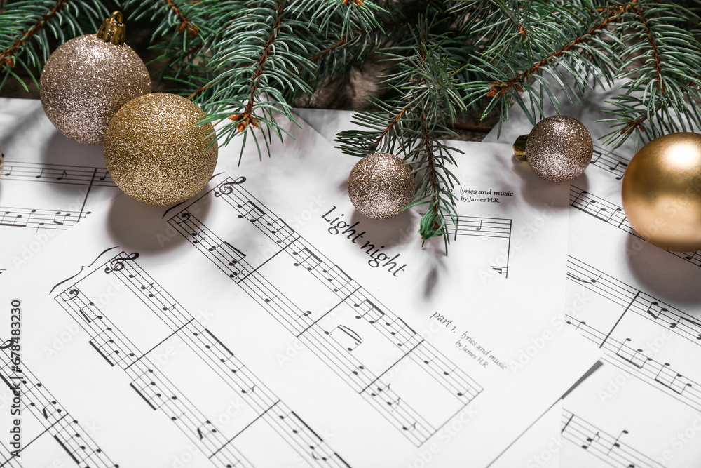 Music sheets, beautiful Christmas balls and fir branches, closeup