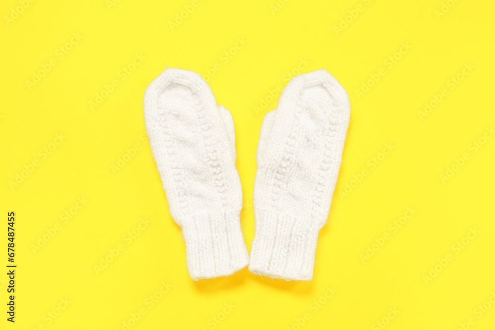 Pair of stylish knitted mittens on yellow background