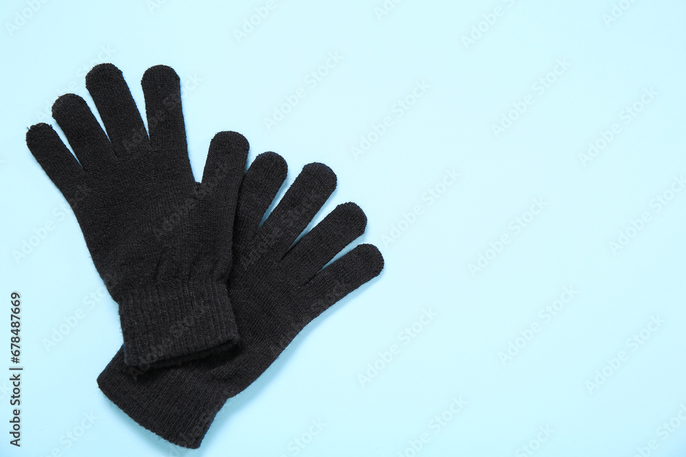 Pair of black warm gloves on color background