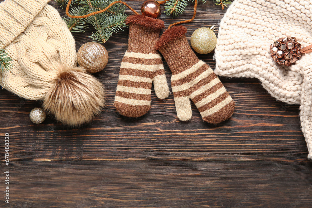 Composition with warm mittens, hat, scarf and Christmas decorations on wooden background