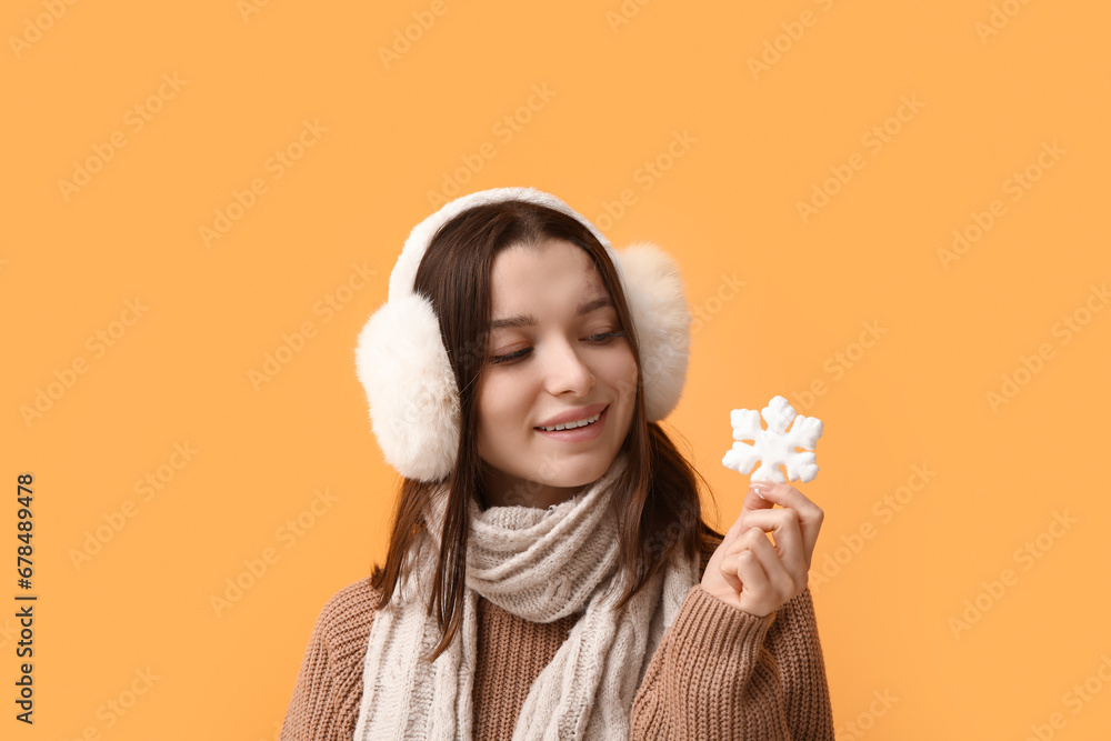 Beautiful young woman with decorative snowflake on yellow background