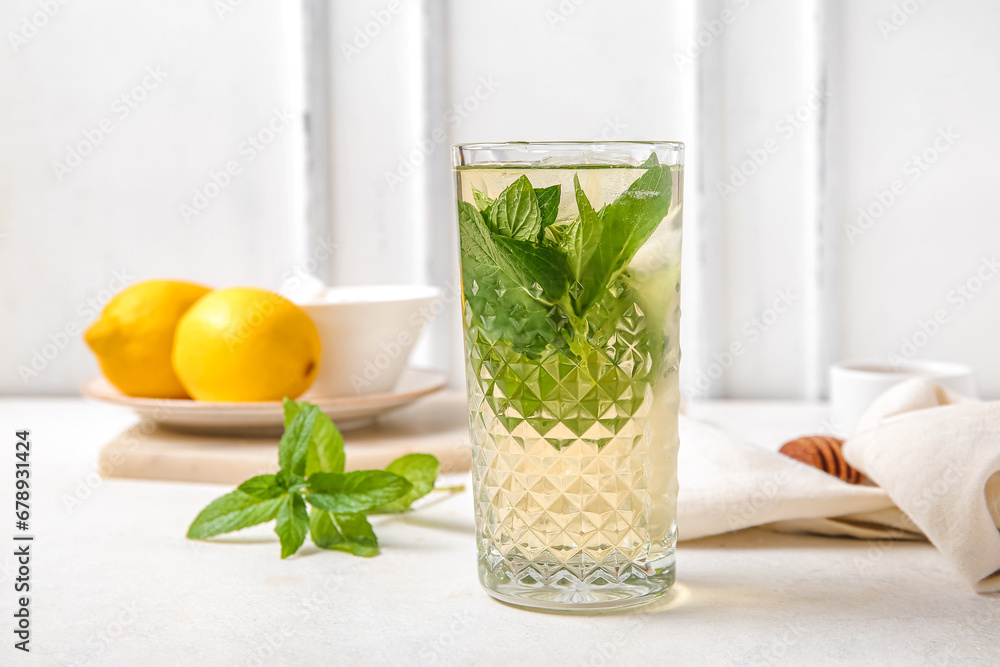 Glass of fresh icy mint tea with lemons on white table