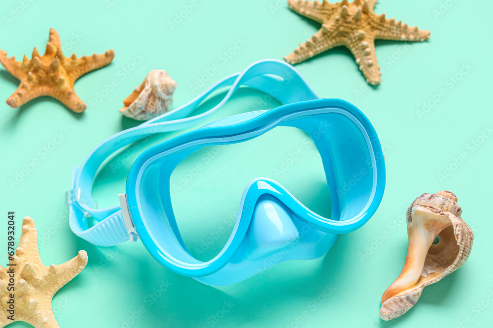 Blue swimming mask and starfish on turquoise background, closeup