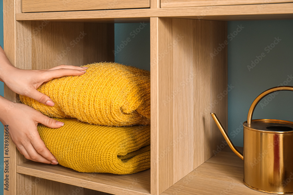 Woman putting clean clothes in wardrobe, closeup