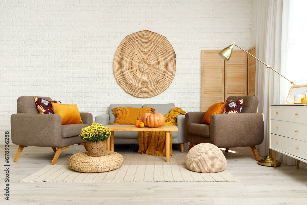 Interior of stylish living room with grey sofa, armchairs, coffee table and flowers