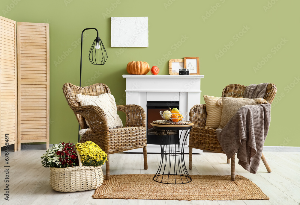 Interior of stylish living room with armchairs, fireplace and pumpkins on coffee table