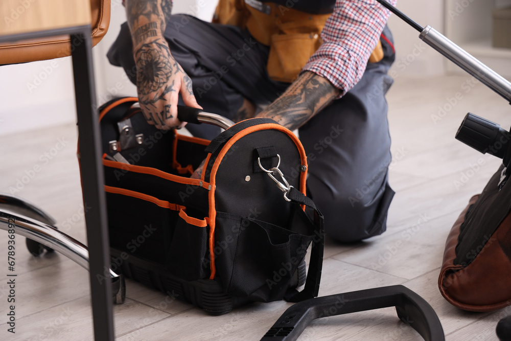 Male worker with bag of tools assembling chair in office, closeup