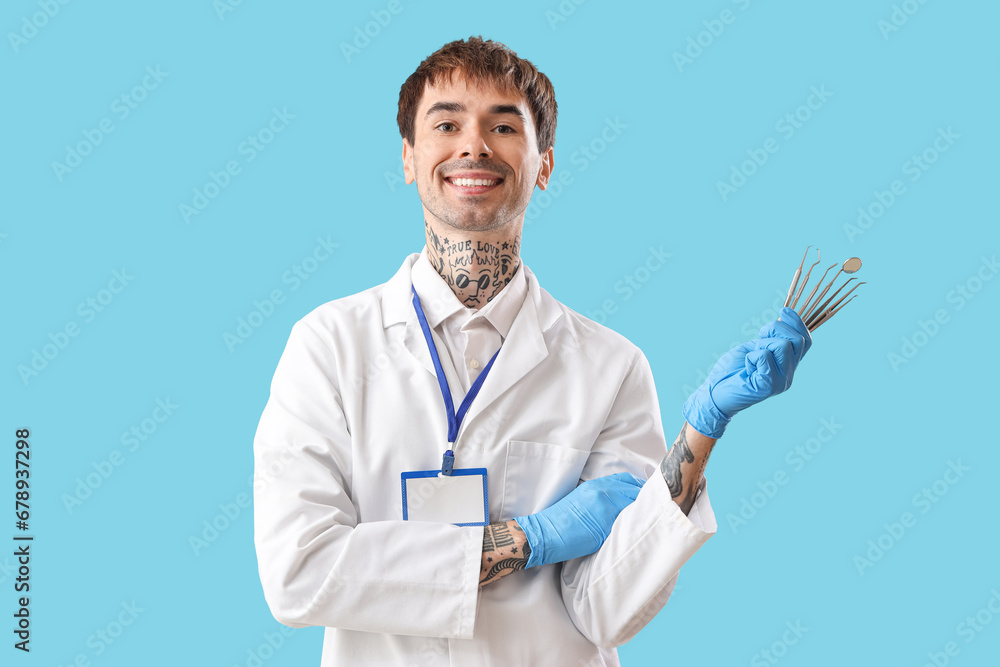 Male dentist with tools on blue background