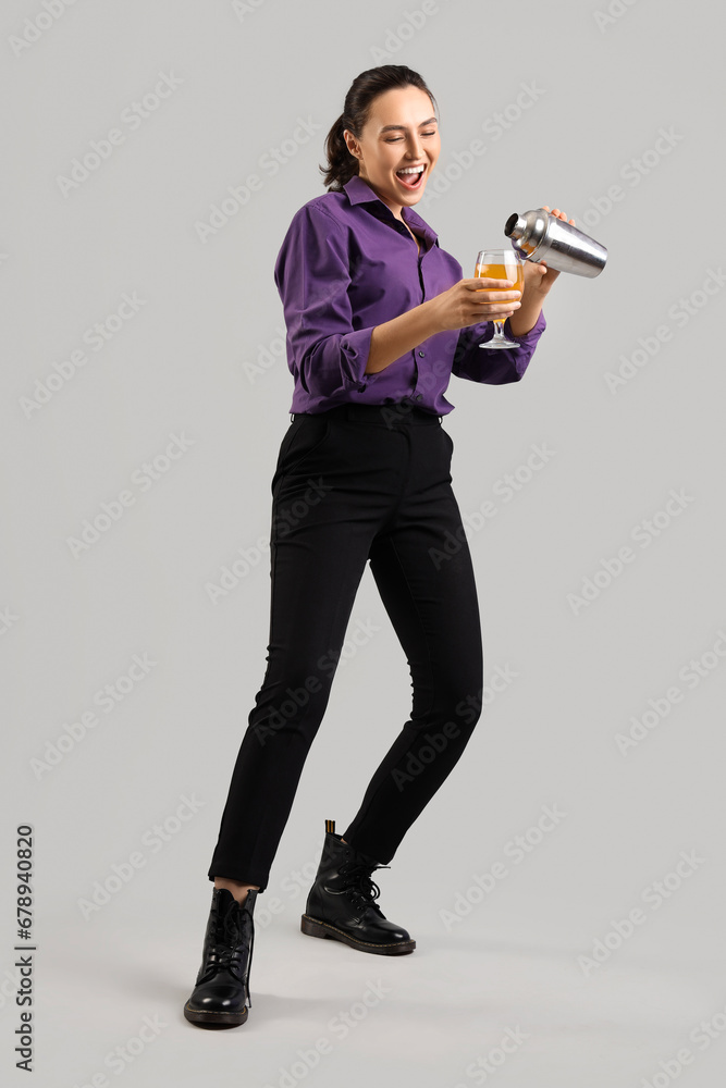 Female bartender with cocktail and shaker on light background