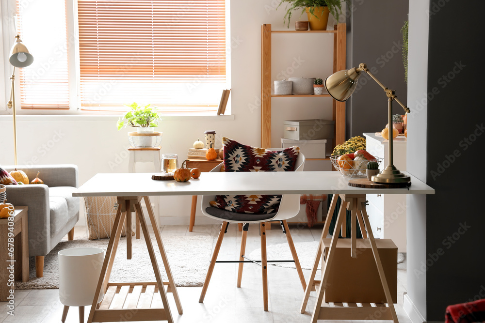 Interior of living room with chrysanthemum flowers, pumpkins and table