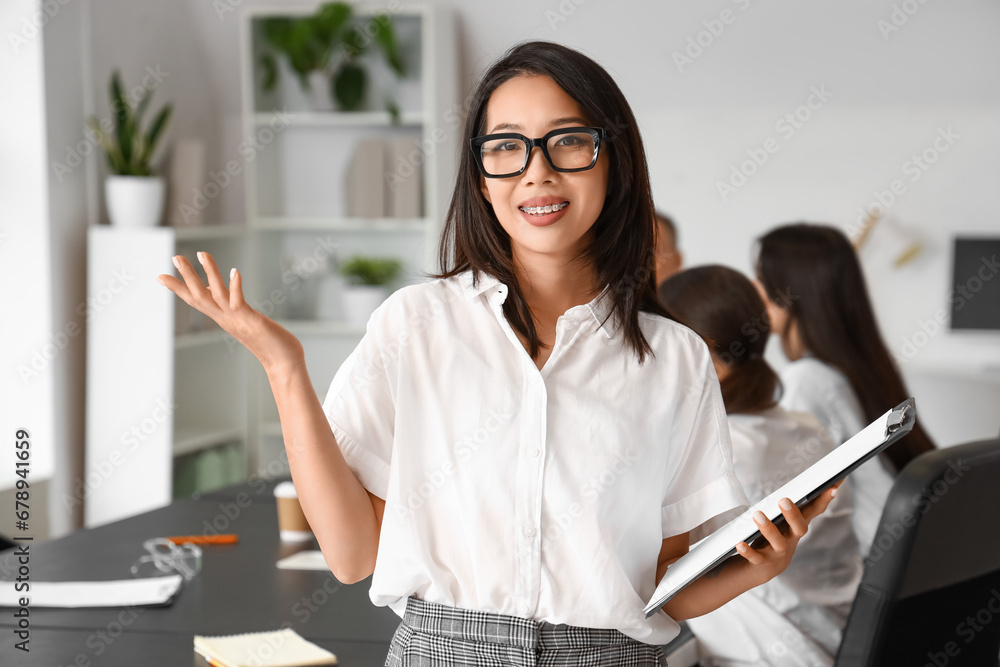 Asian businesswoman with clipboard in office