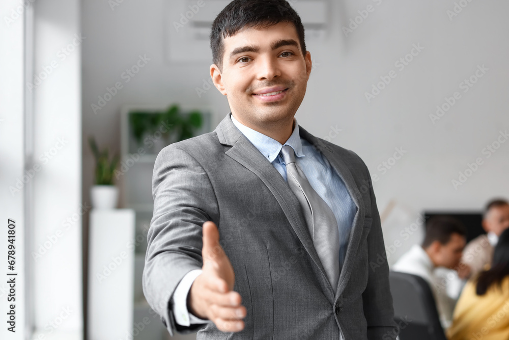 Young businessman reaching out for handshake in office