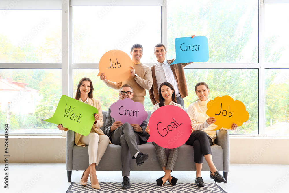 Business colleagues holding speech bubbles with words in office