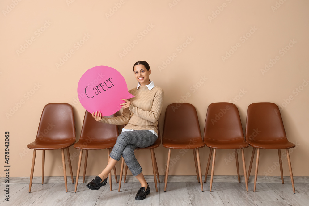 Businesswoman holding speech bubble with word CAREER near beige wall