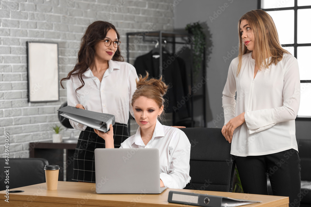 Young women gossiping behind colleagues back in office