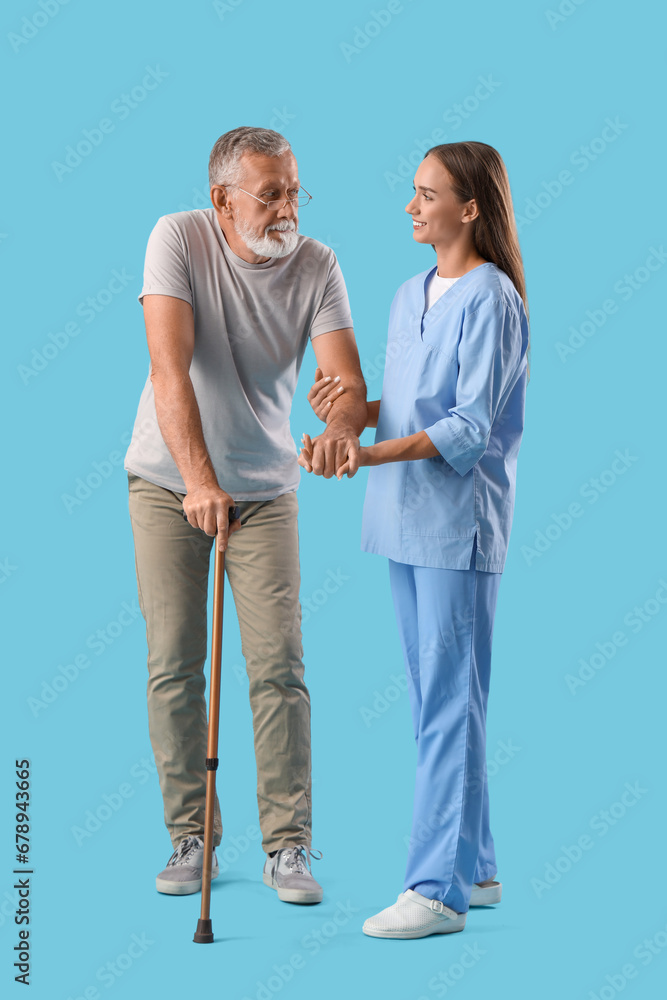 Senior man with walking stick and nurse on blue background