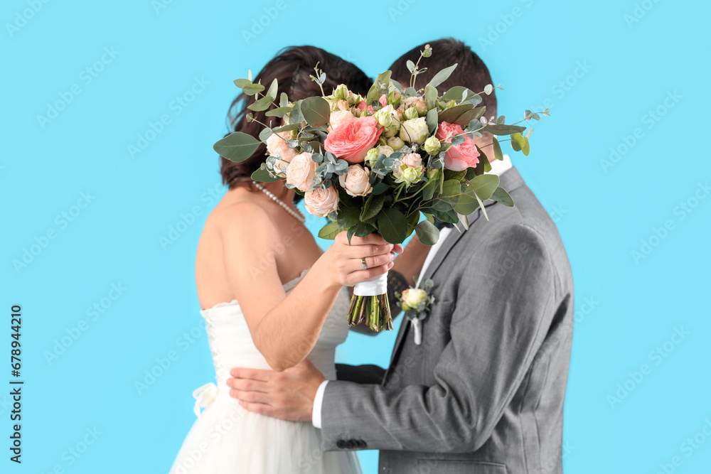 Young wedding couple with bouquet of flowers on blue background