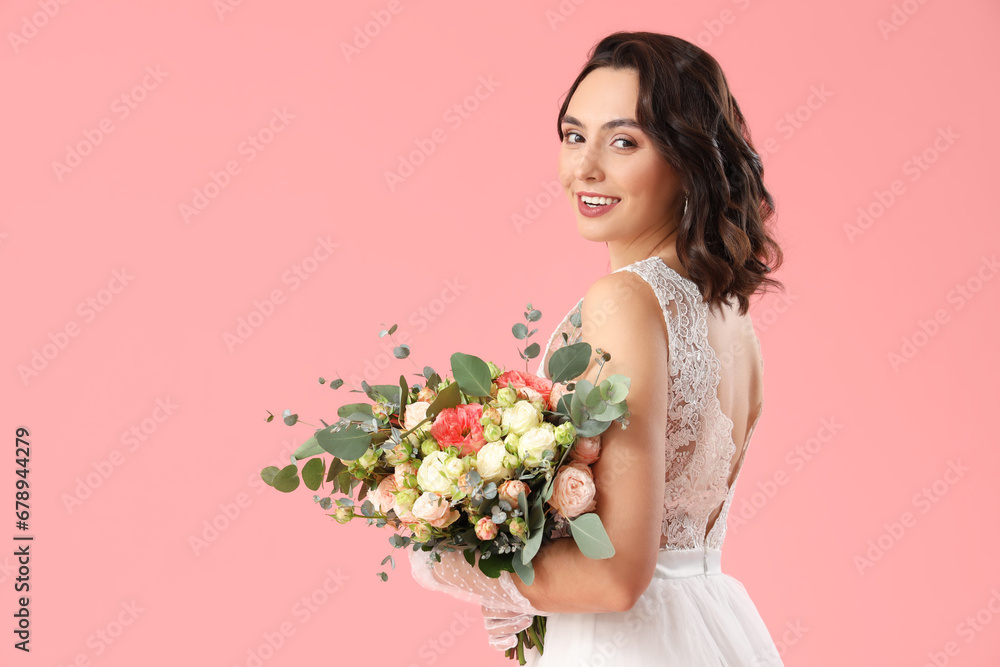 Beautiful bride with wedding bouquet on pink background