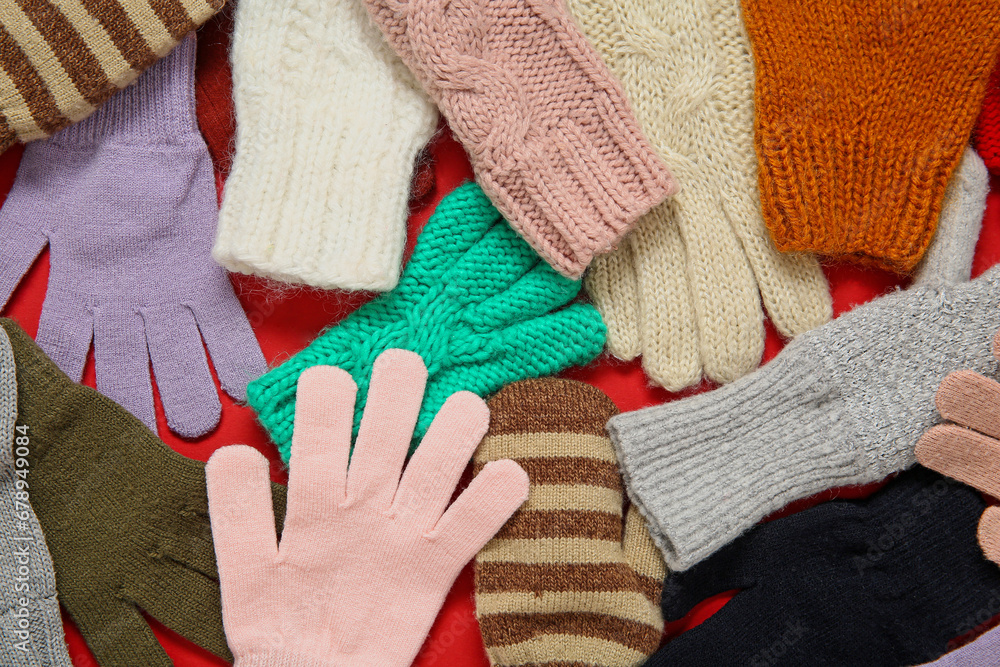 Different warm gloves and mittens on red background, closeup