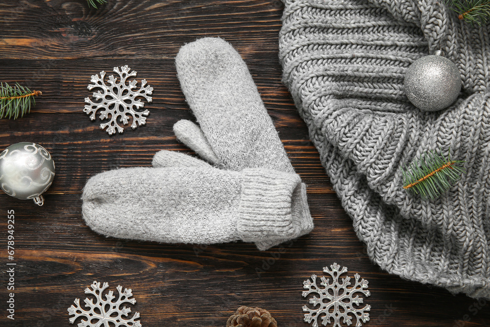 Composition with warm mittens, scarf and Christmas decorations on wooden background