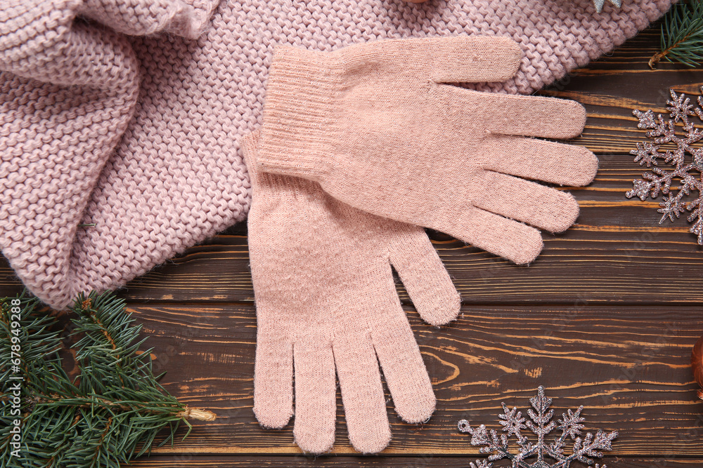 Warm gloves, scarf and Christmas decorations on wooden background