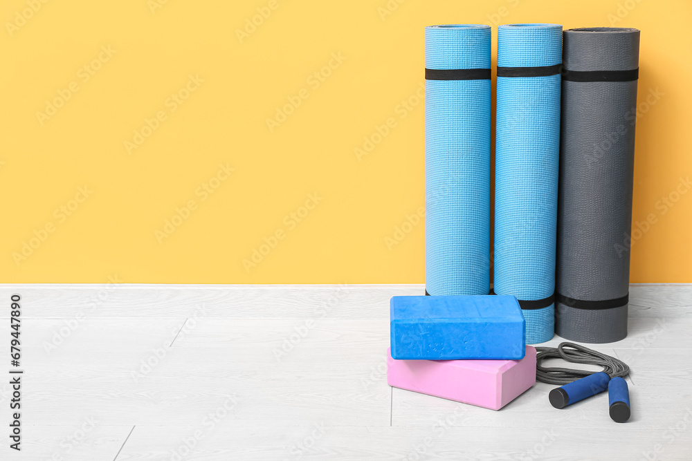 Yoga mats, blocks and skipping rope on floor in gym, closeup