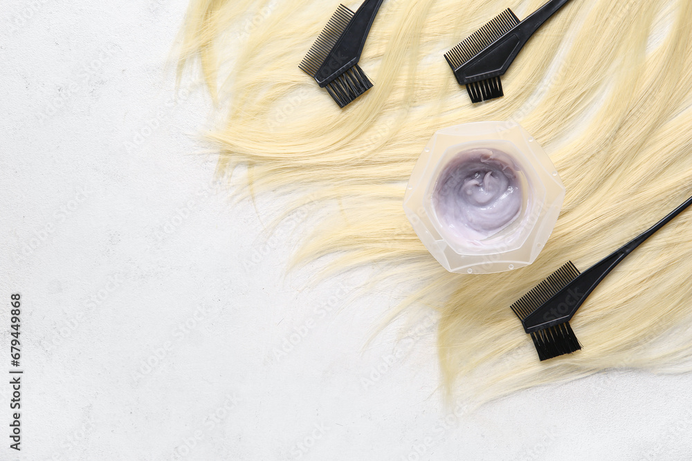 Bowl with hair dye, brushes and blond strand on white background