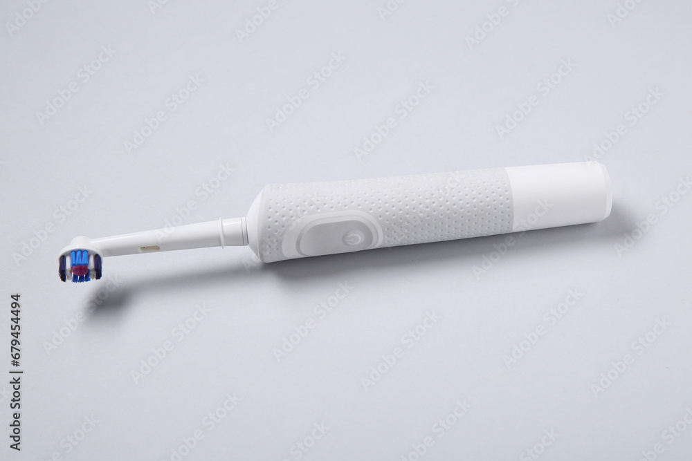 White electric toothbrush on grey background.