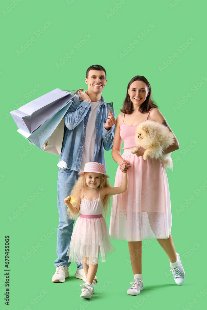 Happy family with dog and shopping bags on green background