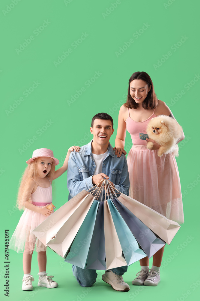 Happy family with dog and shopping bags on green background