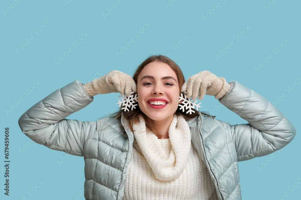 Happy young woman with decorative snowflakes on blue background